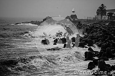Grayscale view of big wave splash against stone formations at the coastline, Valparaiso Editorial Stock Photo