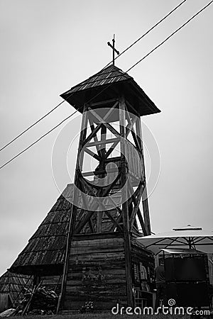 Grayscale of the wooden bell tower with the St. Sava church in the background in Drvengrad Serbia Editorial Stock Photo