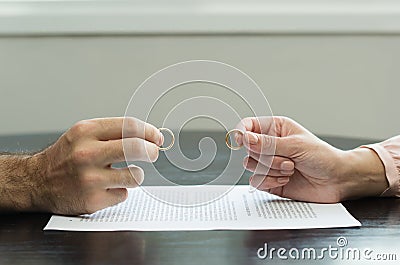 Great concept of divorce, end of relationship, hand of man and woman handing over alliances, divorce agreement Stock Photo