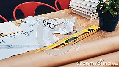 Great designs come from this desk. Still life shot of a pair of spectacles placed on top an architects blueprints in a Stock Photo