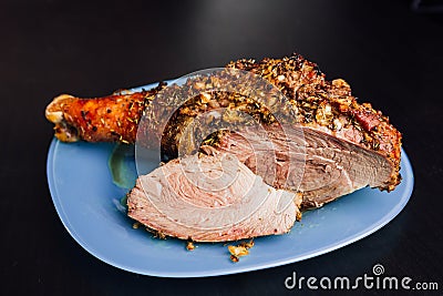 Great fresh baked turkey leg and sliced piece sprinkled with spices lying on a blue plate to black wooden background Stock Photo