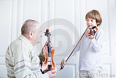 Great grandfather listening to a child playing violin Stock Photo