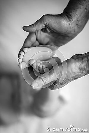 Great-grandmother touching little baby foot, black and white shot, the concept of a family and a new life. into a selective focus Stock Photo