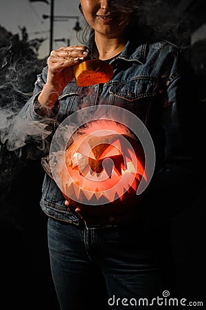 Great halloween pumpkin with burning and smoking mouth and eyes in female hands. Jack-o-lantern Stock Photo