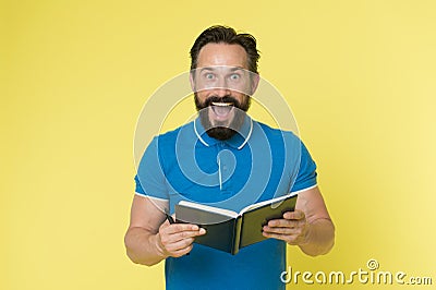 Great idea. Handsome inspired mature man holds notepad looking at camera while standing against yellow background. Man Stock Photo