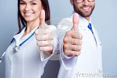 Great job! Close up cropped photo of two medic colleagues in white coats, showing like sign in focus on pure background Stock Photo
