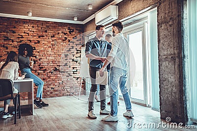 Two men handshake to seal deal, cheerful partners greeting each other in loft office Stock Photo