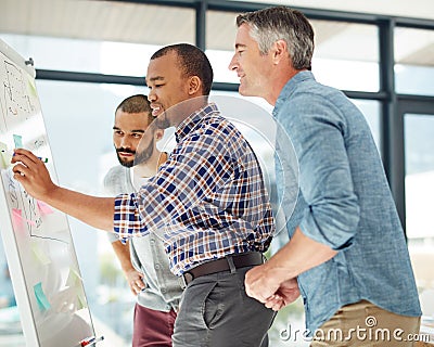 Great minds make the work easy. three businessmen working at a whiteboard. Stock Photo
