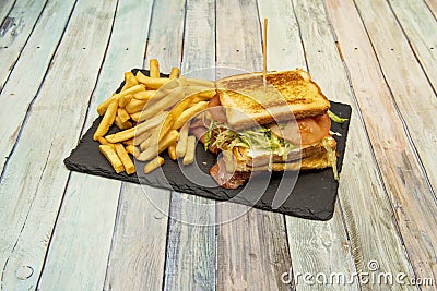 Great mixed sandwich with bacon, lots of melted cheese, fried egg, tomato and lettuce and a side Stock Photo