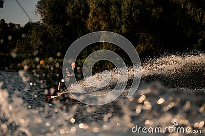 Great view of an active dynamic male wakeboarder who holds rope and energetically riding wakeboard on splashing river Stock Photo