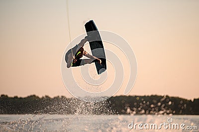 great view of muscular man making trick in jump time with wakeboard against the backdrop of the sky Stock Photo