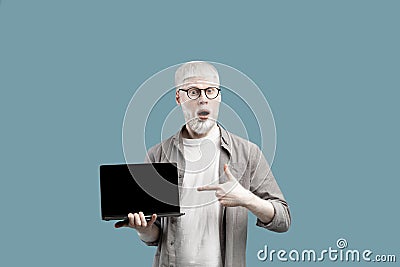 Great website advertisement. Surprised albino man showing laptop empty screen, pointing on it over turquoise background Stock Photo