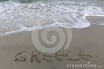 Greece writing on the sand with water coming to erase it Stock Photo