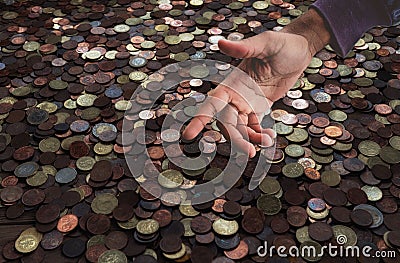 Greediness for money concept, coins background with stretching hand, finance, expenses, savings Stock Photo