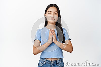 Greedy asian girl scheming, steeple fingers and squinting coy, having evil genius plan, standing thoughtful over white Stock Photo