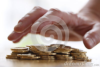 Greedy hand grabbing or reaching out for pile of golden coins. Close up - Concept for tax, fraud and greed Stock Photo