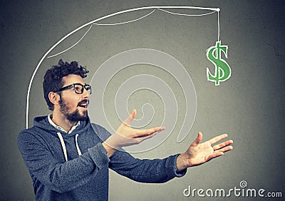 Greedy man chasing dollar bill on gray background. Stock Photo