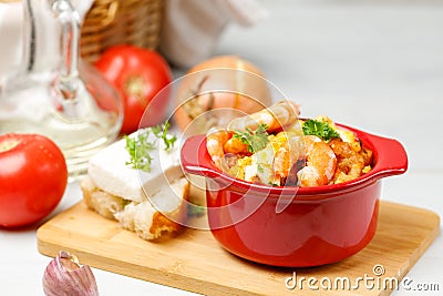 Greek appetizer, Saganaki. Shrimp baked with vegetables and cheese, a portion in a red pot. Close-up, selective focus Stock Photo