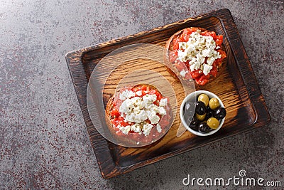 Greek dakos appetizer with barley rusk, tomatoes, feta cheese, oregano and olive oil closeup on the wooden board. Horizontal top Stock Photo