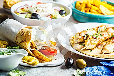 Greek food: salad, chicken souvlaki, gyros and baked potatoes on gray background. Traditional greek cuisine concept Stock Photo