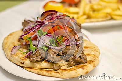 Greek kebab on pita with onions, tomatoes. Traditional Greek Cuisine Stock Photo