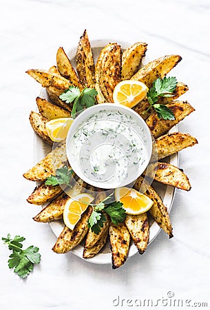 Greek lemon baked potato and tzadziki sauce - delicious snack, appetizer, tapas on a light background, top view Stock Photo