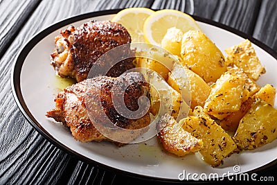 Greek lemon potatoes with garlic and herbs served with chicken thigh grilled close-up. horizontal Stock Photo