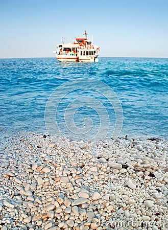 Greek marble beach, blue sea and cruise boat Stock Photo