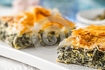 Greek pie spanakopita on the white plate with blurred accessorizes horizontal Stock Photo