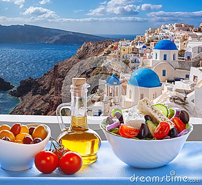 Greek salad against famous church in Oia village, Santorini island in Greece Stock Photo