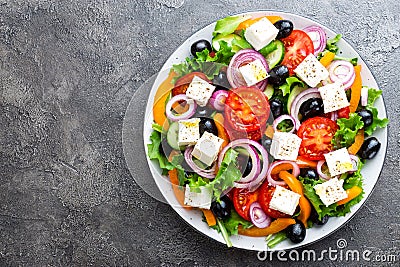 Greek salad. Fresh vegetable salad with tomato, onion, cucumbers, pepper, olives, lettuce and feta cheese. Greek salad Stock Photo