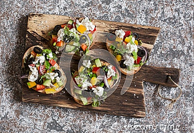 Greek salad style bruschetta on a wooden cutting board. Delicious appetizers for wine or a snack Stock Photo