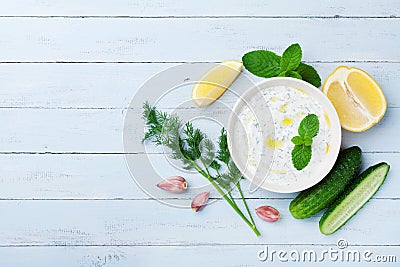 Greek sauce tzatziki from sour cream yogurt on wooden table top view. Traditional mediterranean dip or dressing. Stock Photo