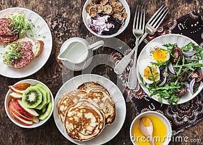 Greek yogurt with whole grain cereals and berry sauce, pancakes, arugula, cherry tomatoes, boiled eggs salad, kiwi, apples fruit, Stock Photo