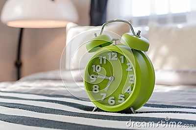 Green alarm clock on bed Stock Photo