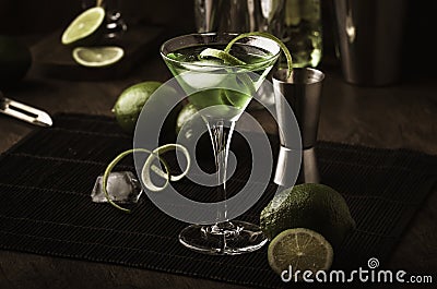 Green alcoholic cocktail monk with dry gin, vermouth, liquor, lime zest and ice, bar tools, dark background Stock Photo