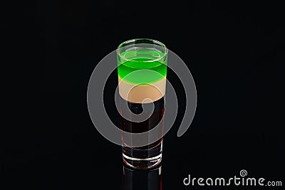 Green alcoholic shot glass with absent, irish cream, liquor on elegant dark black background Stock Photo