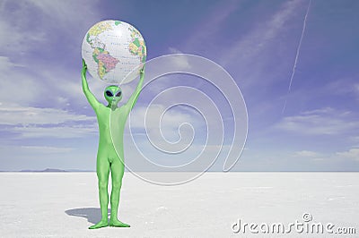 Green Alien Holds Earth Globe Above White Desert Planet Stock Photo