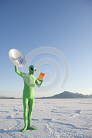 Green Alien Man Holding Tablet and Satellite Dish Stock Photo