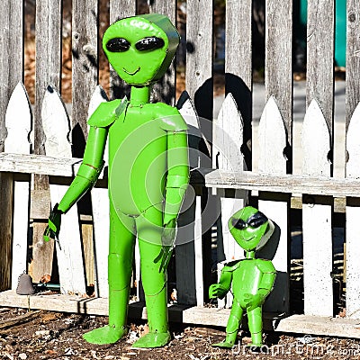 Green Alien Metal Garden Statues and Wooden Fence Stock Photo