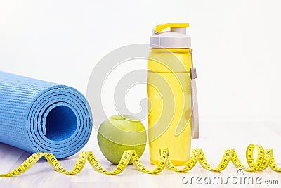 Green apple, measuring tape, water bottle and sports mats on a light wooden background Stock Photo