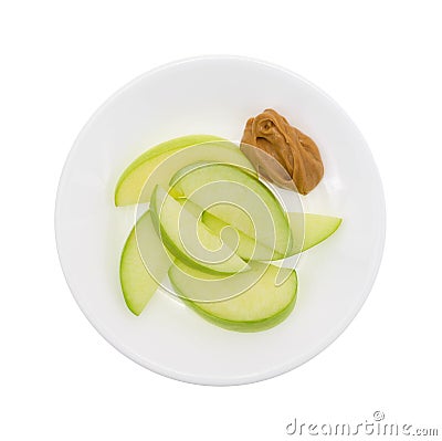 Green apple slices on dish with peanut butter top view Stock Photo