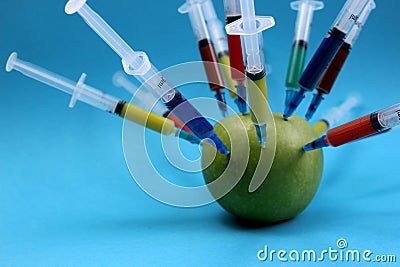 Green apple studded with a multi-colored syringe Stock Photo