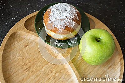 Green apple and sugar donut on the table, the dilemma of what to choose, the concept of healthy eating and lifestyle, the problem Stock Photo