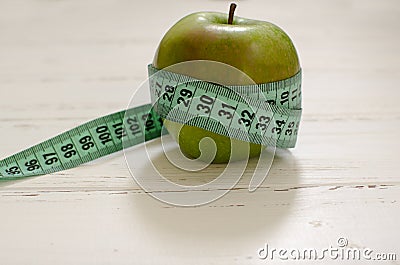 Green apple wrapped in centimeter on white wooden background wit Stock Photo