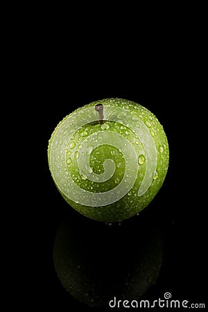 Green Apple with water drops on reflective table, centered. Stock Photo