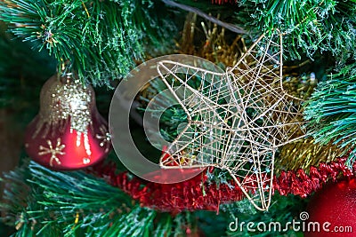 Green artificial Christmas tree decorated with star in a golden frame and interlacing golden threads; red bell with gold glitter Stock Photo