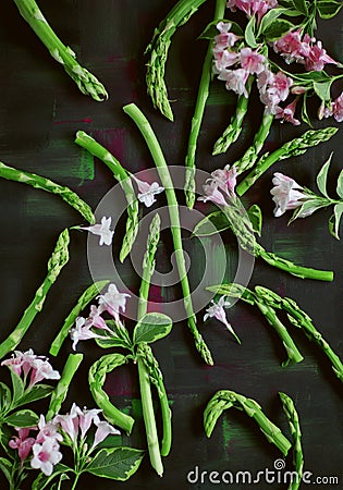 Green asparagus, asparagus tips beautiful arranged on dark wood with pink flowers Stock Photo
