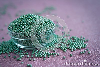 Green ball crystal sugar sprinkle dots, on glitter pink background. Stock Photo