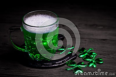 St. Patrick`s Day. Green Beer pint with rusty horseshoe on wooden table, decorated with shamrock leaves. Stock Photo